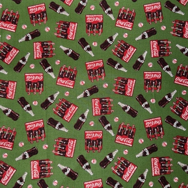 Red Coca-Cola bottle packs and glass bottles on green.